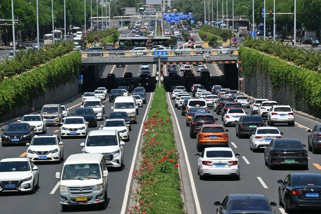 Motorists commute on a road in the Sanlitun business district in Beijing on May 14, 2025. (Photo by ADEK BERRY / AFP)