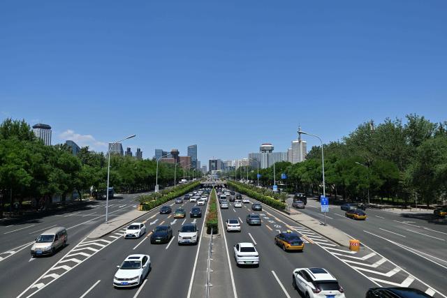 Motorists commute on a road in the Sanlitun business district in Beijing on May 14, 2025. (Photo by ADEK BERRY / AFP)