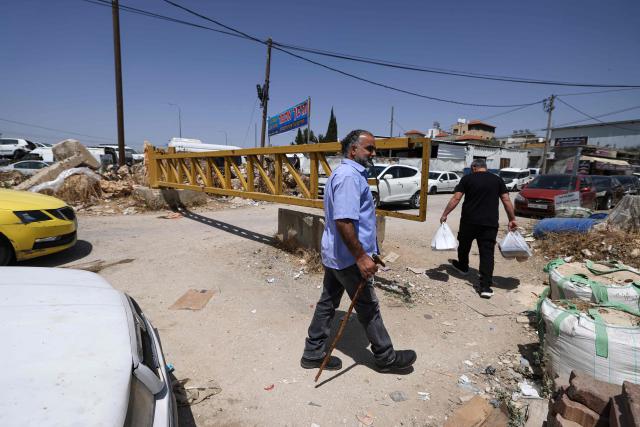 Palestinians cross an metal gate set up by the Israeli army in Sinjil, in the occupied West Bank, on May 12, 2025. Israel heavily restricts the movement of West Bank Palestinians, who must obtain permits from authorities to travel through checkpoints and cross into east Jerusalem or Israel. (Photo by JAAFAR ASHTIYEH / AFP)