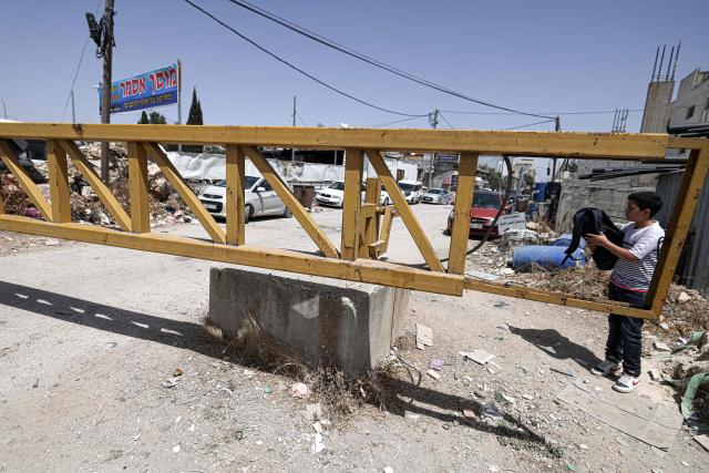 A Palestinian schoolboy crosses an metal gate set up by the Israeli army in Haris, in the occupied West Bank, on May 12, 2025. Israel heavily restricts the movement of West Bank Palestinians, who must obtain permits from authorities to travel through checkpoints and cross into east Jerusalem or Israel. (Photo by JAAFAR ASHTIYEH / AFP)