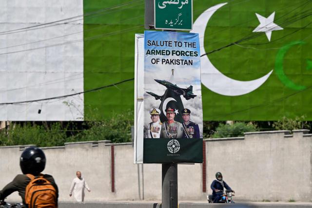 Commuters ride past a billboard featuring Pakistan's Army Chief General Syed Asim Munir (C), Naval Chief Admiral Naveed Ashraf (L) and Air Chief Marshal Zaheer Ahmed Babar Sidhu (R) along a street in Rawalpindi on May 14, 2025. The brief conflict between India and Pakistan last week may have left no clear victor, but Islamabad's generals are taking a win, riding a wave of approval on social media to burnish their recently tarnished image. (Photo by Farooq NAEEM / AFP)