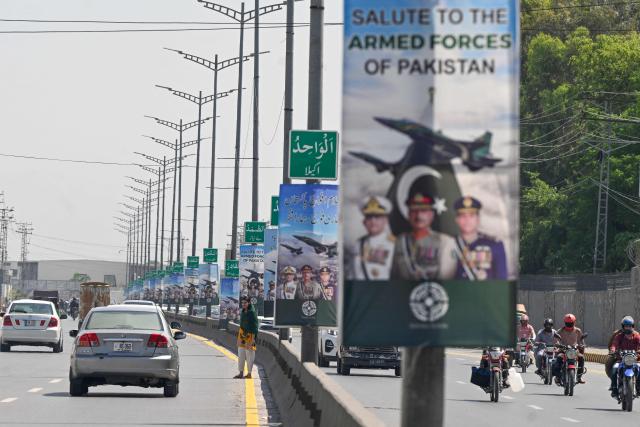 Commuters ride past posters featuring Pakistan's Army Chief General Syed Asim Munir (C), Naval Chief Admiral Naveed Ashraf (L) and Air Chief Marshal Zaheer Ahmed Babar Sidhu (R) along a street in Rawalpindi on May 14, 2025. The brief conflict between India and Pakistan last week may have left no clear victor, but Islamabad's generals are taking a win, riding a wave of approval on social media to burnish their recently tarnished image. (Photo by Farooq NAEEM / AFP)