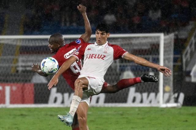 America de Cali's defender #92 Yerson Candelo and Huracan's Argentine midfielder #17 Gabriel Alanis fight for the ball during the Copa Sudamericana group stage football match between Colombia's America de Cali and Argentina's Huracan at the Olimpico Pascual Guerrero stadium in Cali, Valle del Cauca department, Colombia, on May 14, 2025. (Photo by JOAQUIN SARMIENTO / AFP)