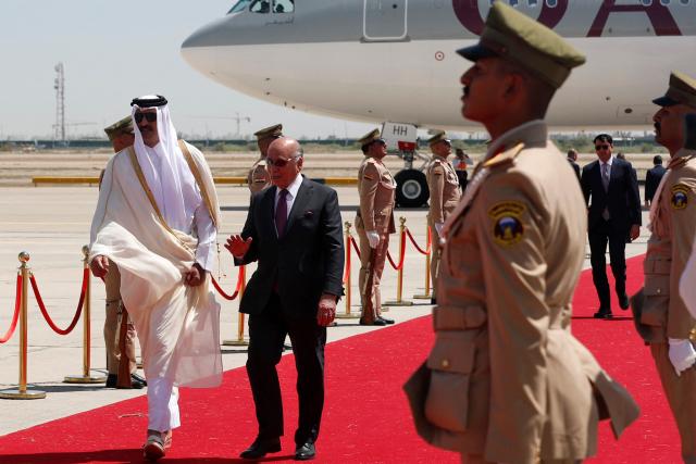 Iraq's Foreign Minister Fuad Hussein (C) walks with Qatar's Emir Sheikh Tamim bin Hamad al-Thani as he arrives in Baghdad ahead of the 34th Arab League summit on May 17, 2025. (Photo by AHMAD AL-RUBAYE / POOL / AFP)