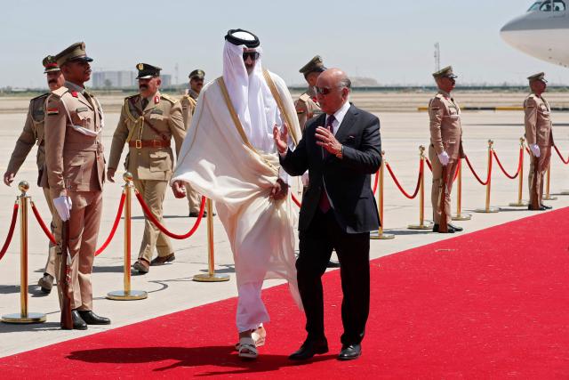 Iraq's Foreign Minister Fuad Hussein (C) walks with Qatar's Emir Sheikh Tamim bin Hamad al-Thani as he arrives in Baghdad ahead of the 34th Arab League summit on May 17, 2025. (Photo by AHMAD AL-RUBAYE / POOL / AFP)