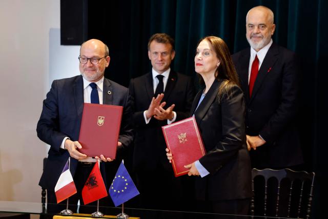 France's President Emmanuel Macron (L) and Albania's Prime Minister Edi Rama look on as Remy Rioux (L), chief executive of the French Development Agency (front L) and Minister of Tourism and Environment of Albani Mirela Kumbaro (front R) pose after signing agreements at the Government Palace, in Tirana on May 17, 2025. (Photo by Ludovic MARIN / AFP)