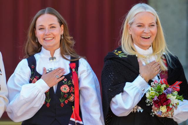 Crown Princess Mette-Marit of Norway (R) and Princess Ingrid Alexandra of Norway react as they greet the children's procession during May 17 celebrations at Skaugum, residence of Norway's Crown Prince, in Asker, soutwest of Oslo, on May 17, 2025. On May 17, Norway marks the signing of the Constitution in 1814. (Photo by Lise Åserud / NTB / AFP) / Norway OUT