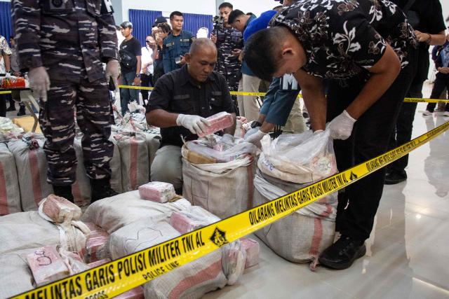 Navy personnel arrange packages of 705 kg methamphetamine and 1.2 tonnes of cocaine seized from a Thai fishing boat before a presser at a naval base in Batam, Riau Islands on May 17, 2025. (Photo by Andaru AK / AFP)