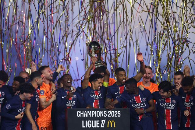 Paris Saint-Germain's Brazilian defender #05 Marquinhos (C) lifts the trophy as as they celebrate their championship title following the French L1 football match between Paris Saint-Germain (PSG) and AJ Auxerre at The Parc des Princes Stadium in Paris on May 17, 2025. (Photo by FRANCK FIFE / AFP)