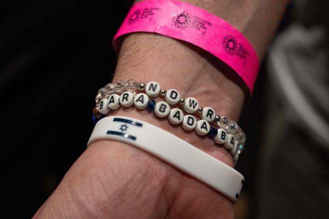 A person wears a bracelet with the Israeli flag and another with the title of Sweden's song entry for the 2025 Eurovision Song Contest as people gather to watch the finals of the contest being screened at a community center in Tel Aviv, Israel, on May 17, 2025. Austria's JJ won the 2025 Eurovision Song Contest on May 18, with his operatic song "Wasted Love" triumphing at the world's biggest live music television event. After the nail-biting drama as the votes were revealed running into Sunday morning, Austria finished with 436 points, ahead of Israel on 357 and Estonia on 356. (Photo by Maya Levin / AFP)