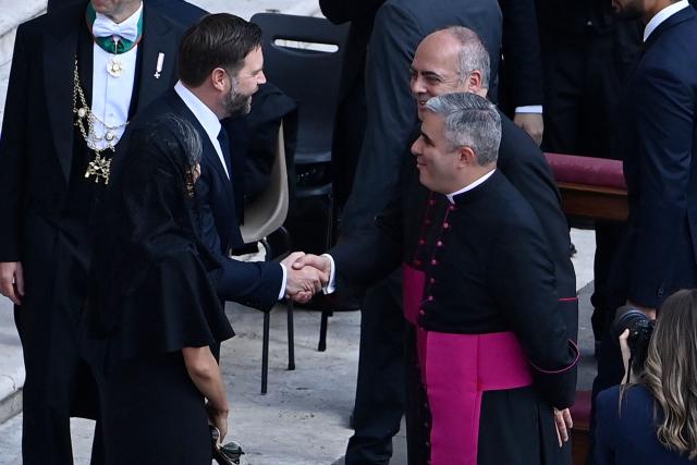 JD US Vice President JD Vance (2ndR) and his wife Usha (L) are greeted as they arrive to attend a Holy Mass for the Beginning of the Pontificate of Pope Leo XIV, in St Peter's square in The Vatican on May 18, 2025. (Photo by Isabella BONOTTO / AFP)