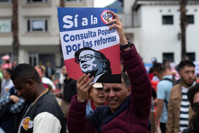 A man holds a sign reading "Yes To the Referendum on the Reforms" during a town meeting after the Senate voted against the government labour reform referendum promoted by Colombia's President Gustavo Petro in Bogota on May 18, 2025. The Colombian Senate rejected on May 14, 2025, to call a popular consultation promoted by President Gustavo Petro for citizens to vote on whether they accept to reform the labor system, as the government intends. (Photo by Alejandro Martinez / AFP)