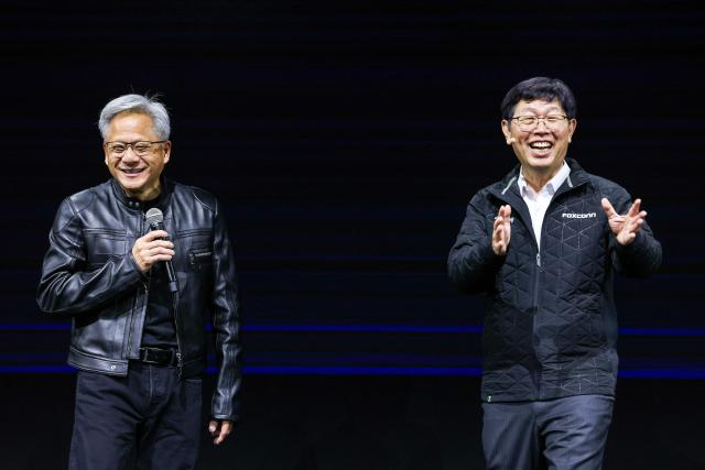 Nvidia co-founder and CEO Jensen Huang (L) shows up as a guest during Foxconn Chairman Young Liu's keynote speech for Computex 2025 at the Taipei Nangang Exhibition Center Hall in Taipei on May 20, 2025. (Photo by I-Hwa Cheng / AFP)