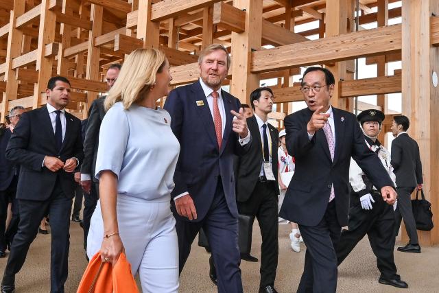 King Willem-Alexander of the Netherlands (C) walks with officials under the wooden "Grand Ring" structure during a visit to the 2025 Osaka Expo to mark Dutch National Day celebrations in the city of Osaka on May 21, 2025. (Photo by Richard A. Brooks / AFP)