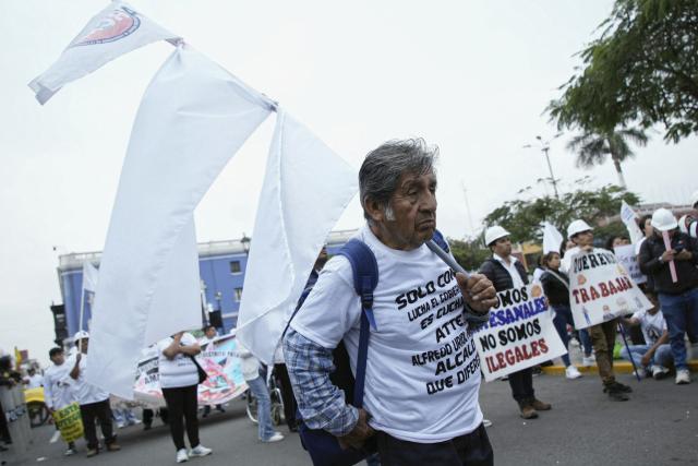 A demonstrator carries white flags as he marches during a protest against the government, the organized crime and calling for the lifting of mining restrictions in Trujillo, Peru on May 21, 2025. (Photo by Steffano Palomino / AFP)