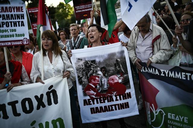 A protestor shouts slogans as she holds a banner (C) showing the Greek and Israeli Prime Ministers and reading “freedom to Palestine” during a demonstration in support to the Palestinian people outside the Israeli embassy in Athens on May 22, 2025. (Photo by Aris MESSINIS / AFP)