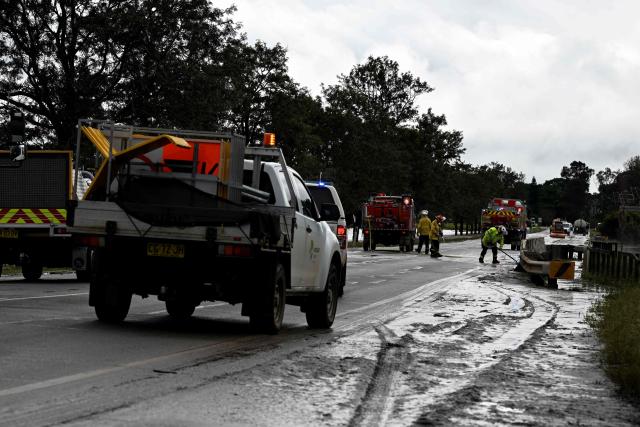 Fire Brigade officials clear silt as floodwaters recede from the main road in Taree on May 23, 2025. Record floods cut a destructive path through eastern Australia on May 23, caking houses in silt, washing out roads and separating 50,000 people from help. (Photo by Saeed KHAN / AFP)