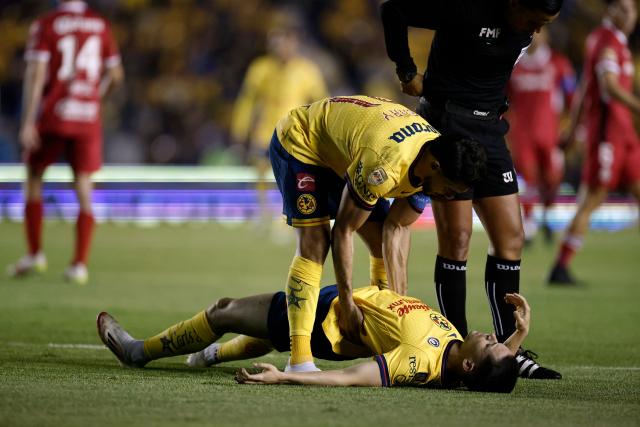 America's Spanish midfielder #08 Alvaro Fidalgo (Bottom) sustains an injury as his teammate America's forward #21 Henry Martin assists him during the Liga MX Clausura tournament final first leg football match between America and Toluca at Ciudad de los Deportes stadium in Mexico City on May 22, 2025. (Photo by Rodrigo Oropeza / AFP)
