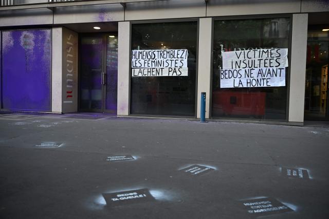Banners reading "Humensis tremble ! Feminists don't let it go." (L) and "Victims insulted. Bedos born before shame" (R) are seen on the facade of the publishing house Humensis following an action by activists from the feminist collective "NousToutes"  to protest against the publication of  Nicolas Bedos' latest book “La soif de honte” in Paris, on May 23, 2025. French actor-writer-director Nicolas Bedos was sentenced at first instance on October 2024 to one year in prison with six months suspended for sexually assaulting two women. (Photo by Leo VIGNAL / AFP)