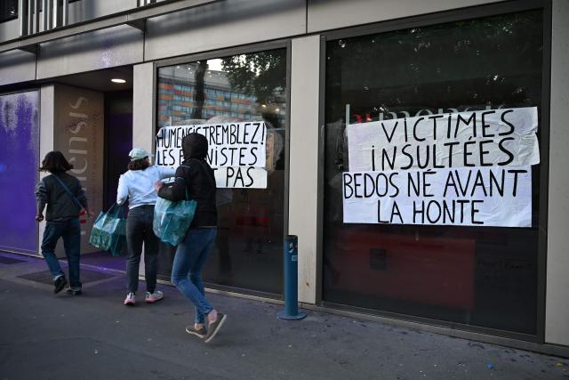 Banners reading "Humensis tremble ! Feminists don't let it go." (L) and "Victims insulted. Bedos born before shame" (R) are seen on the facade of the publishing house Humensis following an action by activists from the feminist collective "NousToutes"  to protest against the publication of  Nicolas Bedos' latest book “La soif de honte” in Paris, on May 23, 2025. French actor-writer-director Nicolas Bedos was sentenced at first instance on October 2024 to one year in prison with six months suspended for sexually assaulting two women. (Photo by Leo VIGNAL / AFP)