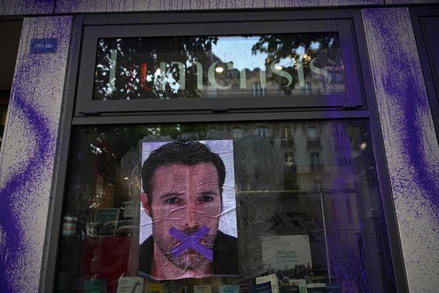 A picture of Nicolas Bedos with a cross over the mouth is seen on the facade of the publishing house Humensis following an action by activists from the feminist collective "NousToutes"  to protest against the publication of  Nicolas Bedos' latest book “La soif de honte” in Paris, on May 23, 2025. French actor-writer-director Nicolas Bedos was sentenced at first instance on October 2024 to one year in prison with six months suspended for sexually assaulting two women. (Photo by Leo VIGNAL / AFP)