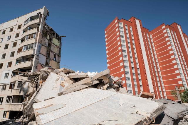 This photograph taken on May 24, 2025 shows a newly built residential building (R) next to a residential building, that was destroyed as a result of a missile attack in 2022, in Kharkiv, amid the Russian invasion of Ukraine. (Photo by Ivan SAMOILOV / AFP)