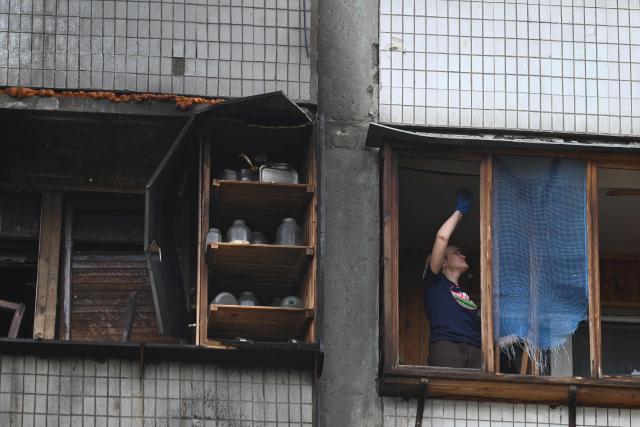 A local resident of a multistory residential building clears debris from her flat damaged following a Russian drone strike on Kyiv on May 24, 2025, amid Russian invasion in Ukraine. At least eight people were wounded in a drone and missile attack on Kyiv on May 24, 2025, city authorities said, just as Russia and Ukraine were in the middle of a major prisoner swap. (Photo by Sergei SUPINSKY / AFP)