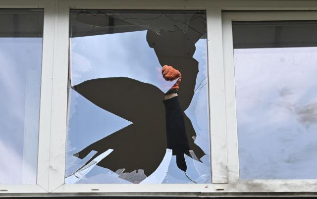 A local resident of multistorey residential building clears broken glass in a flat damaged following a Russian drone strike in Kyiv on May 24, 2025, amid Russian invasion in Ukraine. At least eight people were wounded in a drone and missile attack on Kyiv on May 24, 2025, city authorities said, just as Russia and Ukraine were in the middle of a major prisoner swap. (Photo by Sergei SUPINSKY / AFP)