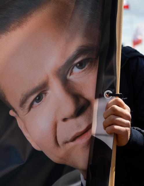 A man holds a banner with a picture of Poland's presidential candidate Karol Nawrocki as his supporters gather to attend a campaign rally in Warsaw on May 25, 2025, a week ahead of the second round of presidential elections. The June 1, 2025 runoff is expected to be a tight contest between pro-EU Warsaw mayor Rafal Trzaskowski, who is backed by the centrist government and won round one by a narrow margin, and nationalist historian Karol Nawrocki, who is supported by the main right-wing opposition. The election comes at a fraught moment for Europe, as Russia's invasion of Ukraine drags on and ties with Washington are under strain. (Photo by Wojtek RADWANSKI / AFP)