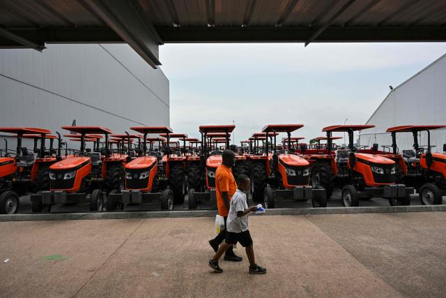 Visitors walks past agricutural tractors during the 7th International Exhibition of Agriculture and Animals Resources (SARA-2025)at the Parcs des expositions in Abidjan on May 25, 2025 (Photo by Issouf SANOGO / AFP)