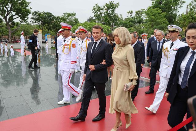 France's President Emmanuel Macron (C) and his wife Brigitte Macron (C-R) take part in a wreath-laying ceremony at the monument of national heroes and martyrs in Hanoi on May 26, 2025. (Photo by Ludovic MARIN / AFP)