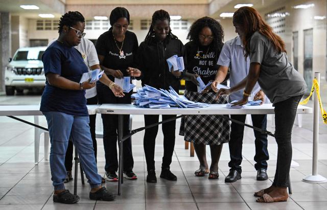 Election staffers check ballot papers during the vote count at a polling station during parliamentary elections in Paramaribo on May 25, 2025. S. Suriname began counting votes in parliamentary elections that will decide who will be responsible for distributing the South American country's new-found oil wealth. (Photo by Juan BARRETO / AFP)