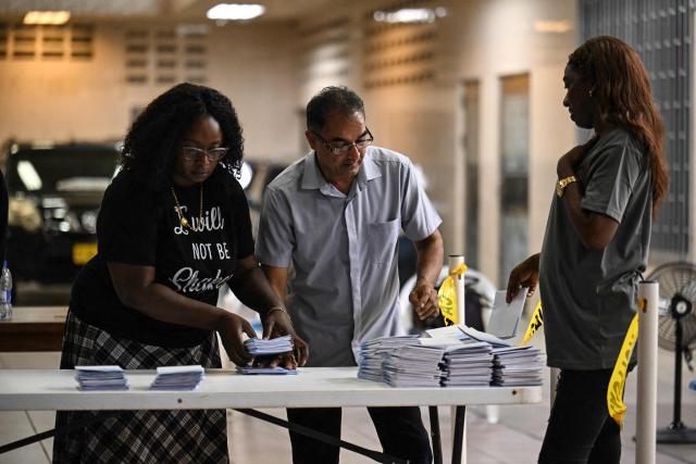 Election staffers check ballot papers during the vote count at a polling station during parliamentary elections in Paramaribo on May 25, 2025. S. Suriname began counting votes in parliamentary elections that will decide who will be responsible for distributing the South American country's new-found oil wealth. (Photo by Juan BARRETO / AFP)