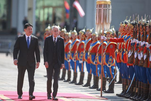 Mongolia's President Ukhnaagiin Khurelsukh (L) and Austria's President Alexander Van der Bellen review the honour guard during a welcome ceremony at Sukhbaatar Square in Ulaanbaatar on May 26, 2025. (Photo by Byambasuren BYAMBA-OCHIR / AFP)