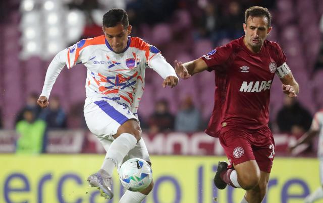 Puerto Cabello's forward #25 Junior Paredes scores his team's first goal past Lanus' defender #24 Carlos Izquierdoz during the Copa Sudamericana group stage football match between Argentina's Lanus and Venezuela's Academia Puerto Cabello at the Ciudad de Lanus stadium, in Lanus, Buenos Aires province, Argentina, on May 27, 2025. (Photo by MARCOS BRINDICCI / AFP)