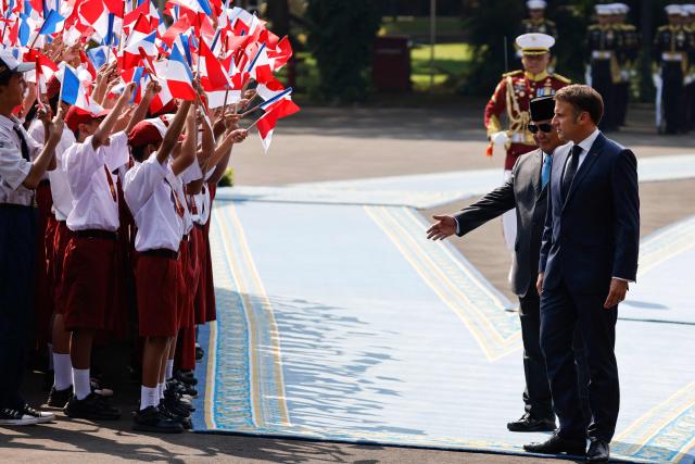 Children waving the flags of Indonesia and France are seen as Indonesia's President Prabowo Subianto (C) receives France's President Emmanuel Macron during a welcoming ceremony at Merdeka Palace in Jakarta on May 28, 2025. (Photo by Ludovic MARIN / AFP)