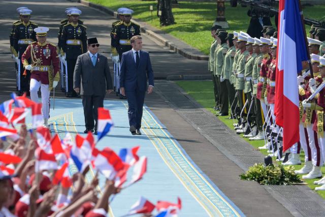 Indonesia's President Prabowo Subianto (centre L) and France's President Emmanuel Macron (C) observe an honour guard during a welcoming ceremony at Merdeka Palace in Jakarta on May 28, 2025. (Photo by BAY ISMOYO / AFP)