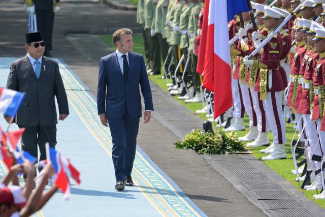 Indonesia's President Prabowo Subianto (L) and France's President Emmanuel Macron (C) observe an honour guard during a welcoming ceremony at Merdeka Palace in Jakarta on May 28, 2025. (Photo by BAY ISMOYO / AFP)