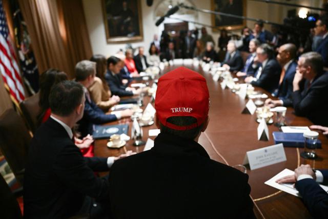 (FILES) Elon Musk, wearing a red hat, looks on as US President Donald Trump hosts a cabinet meeting in the Cabinet Room of the White House on March 24, 2025, in Washington, DC. Elon Musk confirmed that he is leaving his US government role in a post on X (formerly Twitter) on May 28, 2025. (Photo by Brendan SMIALOWSKI / AFP)
