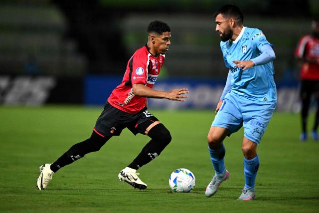 Caracas' forward #14 Ender Echenique runs with the ball past Iquique's midfielder #20 Diego Orellana during the Copa Sudamericana group stage football match between Venezuela's Caracas FC and Chile's Deportes Iquique at the Olimpico UCV stadium in Caracas on May 29, 2025. (Photo by Federico PARRA / AFP)