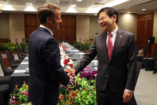 France's President Emmanuel Macron (L) shakes hands with Singapore's Prime Minister Lawrence Wong in Singapore on May 30, 2025. (Photo by Ludovic MARIN / AFP)