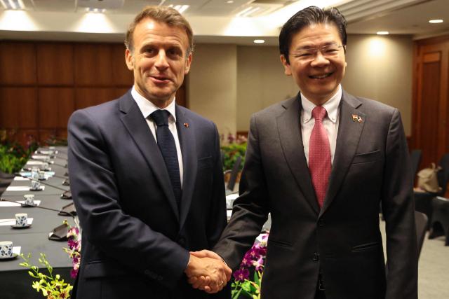 France's President Emmanuel Macron (L) shakes hands with Singapore's Prime Minister Lawrence Wong in Singapore on May 30, 2025. (Photo by Ludovic MARIN / AFP)