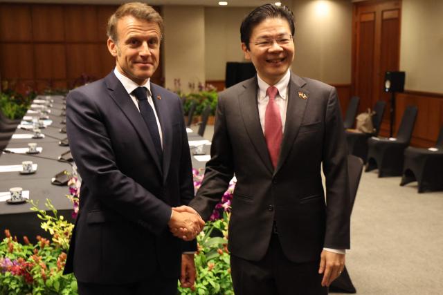 France's President Emmanuel Macron (L) shakes hands with Singapore's Prime Minister Lawrence Wong in Singapore on May 30, 2025. (Photo by Ludovic MARIN / AFP)