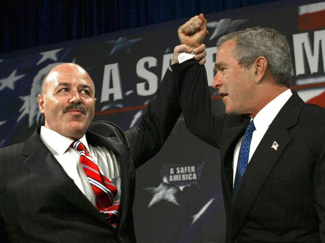 (FILES) Bernard Kerik, former police comissioner of New York City (L), holds the hand of US President George W. Bush in a victory pose as Bush is introduced 18 October 2004 to a crowd of supporters at the Evesham Recreation Center in Marlton, New Jersey. Former NYPD Commissioner Bernard Kerik died on May 29, 2025 at the age of 69. In a post on social media, FBI Director Kash Patel said Kerik passed away on Thursday after a private battle with an illness. Kerik was former New York City Mayor Rudy Giuliani's commissioner from 2000 to 2001, and served during the 9/11 terrorist attacks. (Photo by Paul J. RICHARDS / AFP)