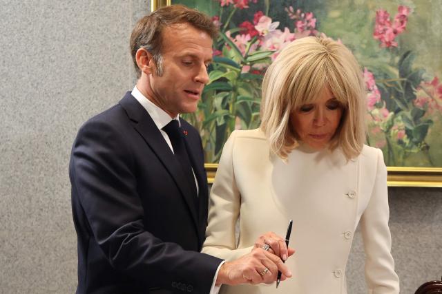 France's President Emmanuel Macron and his wife Brigitte prepare to sign in a book at the Parliament House in Singapore on May 30, 2025. (Photo by Ludovic MARIN / POOL / AFP)
