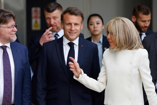 France's President Emmanuel Macron (C) walks with his wife Brigitte Macron (R) during a reception for members of the French community at the International French School (IFS) in Singapore on May 30, 2025. (Photo by Ludovic MARIN / AFP)