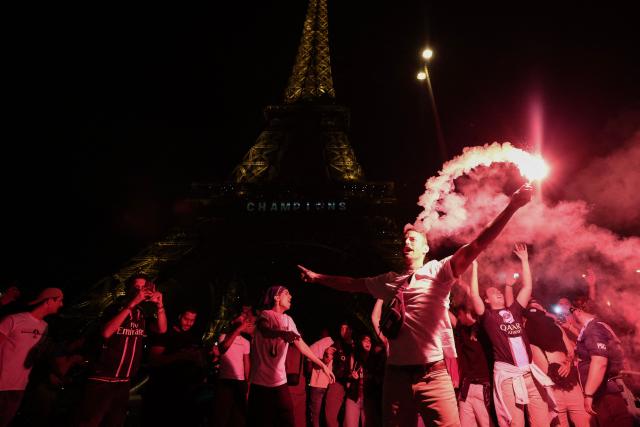 Paris Saint-Germain's supporters light smoke flares in front of The Eiffel Tower in Paris on May 31, 2025, during celebrations following their 5-0 victory in the UEFA Champions League final football match between Paris Saint-Germain (PSG) and Inter Milan held in Munich. (Photo by Thibaud MORITZ / AFP)