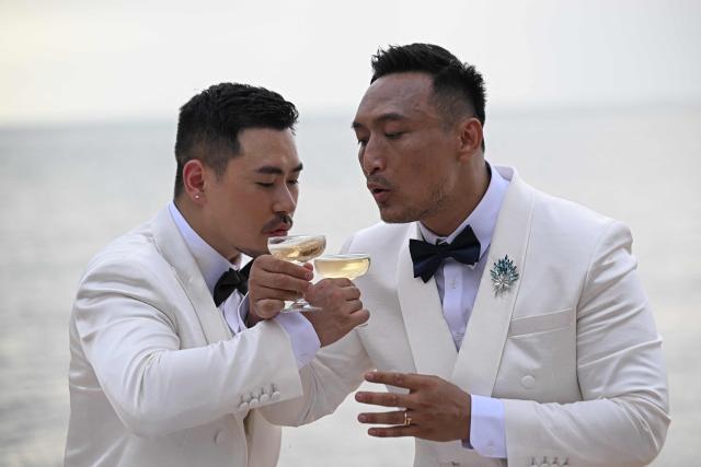 Chinese nationals Song Jihan (L) and Wang Zengyi (R) drink champagne during their wedding ceremony near Pattaya in Chonburi province on May 31, 2025. When Wang Zengyi, 41, and Song Jihan, 29, first met at a friend's dinner party in China, it was love at first sight. Nearly three years later, the gay Chinese couple are getting married in Thailand, which became Asia's largest nation to legalise same-sex marriage earlier this year - including for foreign couples. (Photo by Lillian SUWANRUMPHA / AFP) / To go with Thailand-China-rights-LGBTQ, REPORTAGE by Sarah LAI (STF), Sally JENSEN