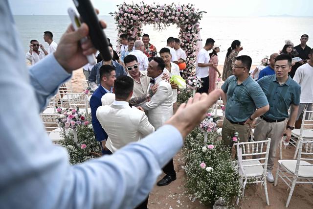 Chinese nationals Song Jihan and Wang Zengyi are embraced by loved ones during their wedding ceremony near Pattaya in Chonburi province on May 31, 2025. When Wang Zengyi, 41, and Song Jihan, 29, first met at a friend's dinner party in China, it was love at first sight. Nearly three years later, the gay Chinese couple are getting married in Thailand, which became Asia's largest nation to legalise same-sex marriage earlier this year - including for foreign couples. (Photo by Lillian SUWANRUMPHA / AFP) / To go with Thailand-China-rights-LGBTQ, REPORTAGE by Sarah LAI (STF), Sally JENSEN