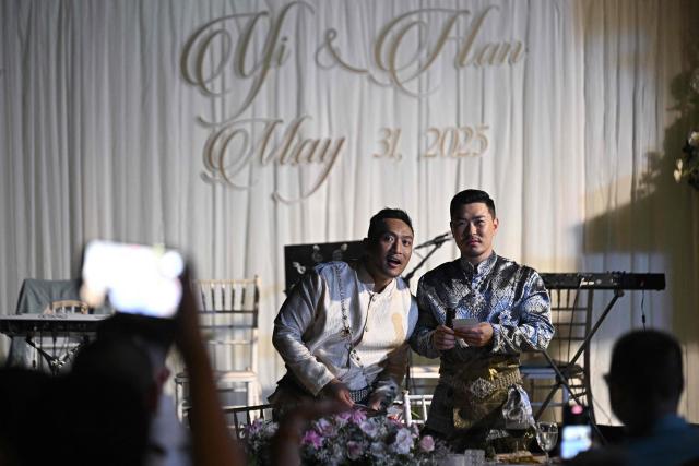 Chinese nationals Song Jihan (R) and Wang Zengyi (L) speak during their wedding reception near Pattaya in Chonburi province on May 31, 2025. When Wang Zengyi, 41, and Song Jihan, 29, first met at a friend's dinner party in China, it was love at first sight. Nearly three years later, the gay Chinese couple are getting married in Thailand, which became Asia's largest nation to legalise same-sex marriage earlier this year - including for foreign couples. (Photo by Lillian SUWANRUMPHA / AFP) / To go with Thailand-China-rights-LGBTQ, REPORTAGE by Sarah LAI (STF), Sally JENSEN
